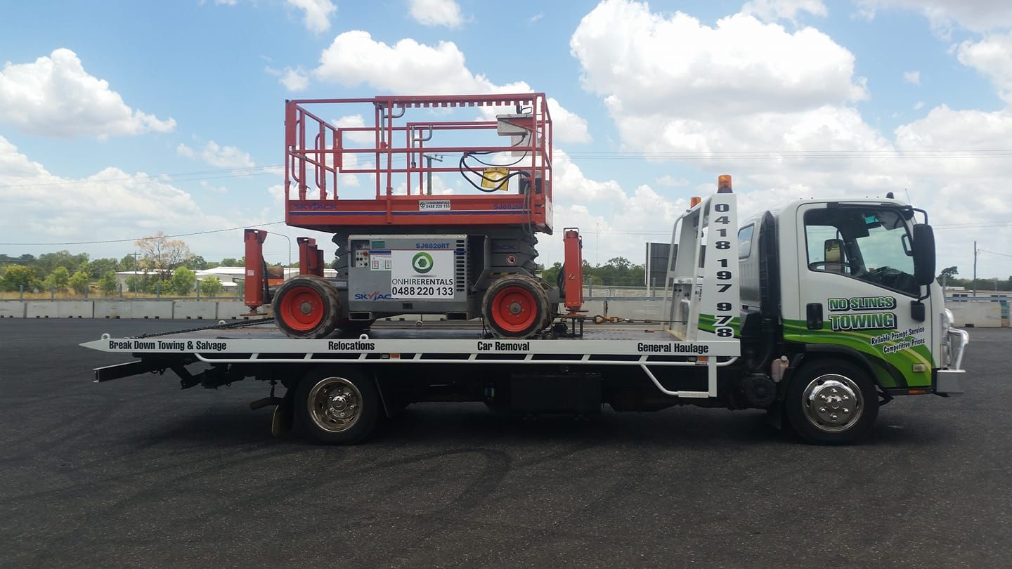 Truck Carrying a Red and Gray Scissor Lift in an Asphalt Lot on a Sunny Day — No Slings Towing in Glendale, QLD