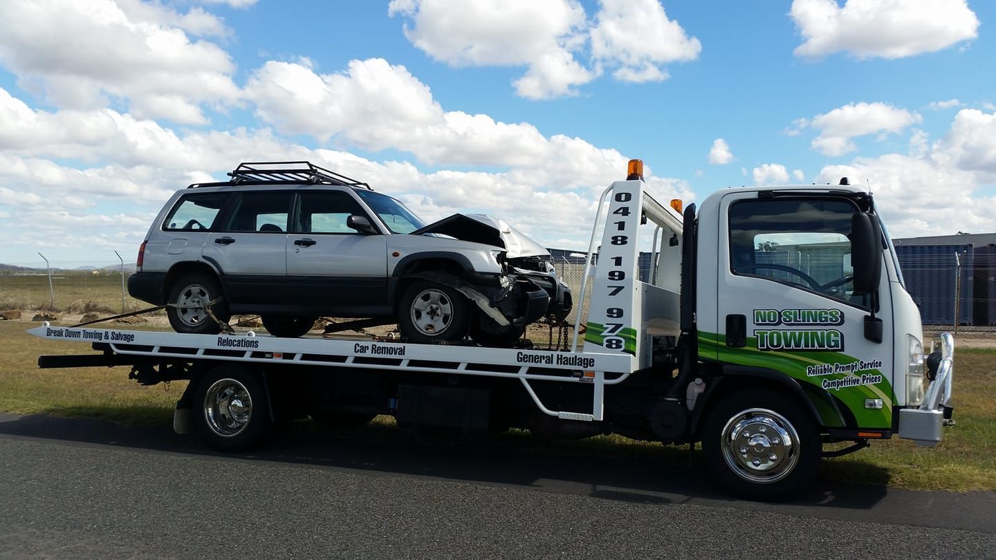 Tow Truck Carrying a Damaged Silver Suv on a Sunny Day — No Slings Towing in Glendale, QLD