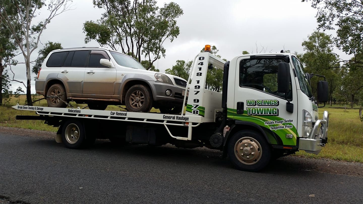 Tow Truck Carrying a Dirty, Silver SUV on a Rural Road — No Slings Towing in Glendale, QLD