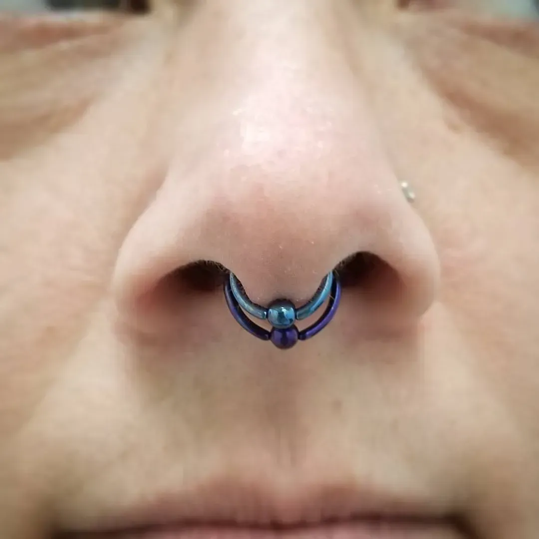 A close up of a woman 's nose with a blue nose ring.