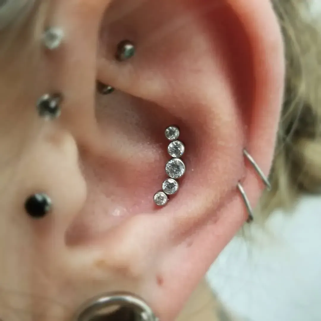 A close up of a woman 's ear with multiple piercings