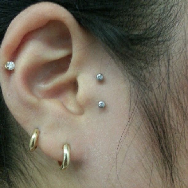 A close up of a woman 's ear with multiple piercings