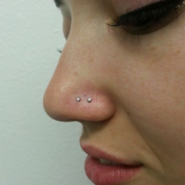 A close up of a woman 's nose with two piercings