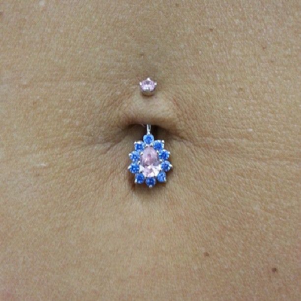 A belly button piercing with a flower shaped pendant