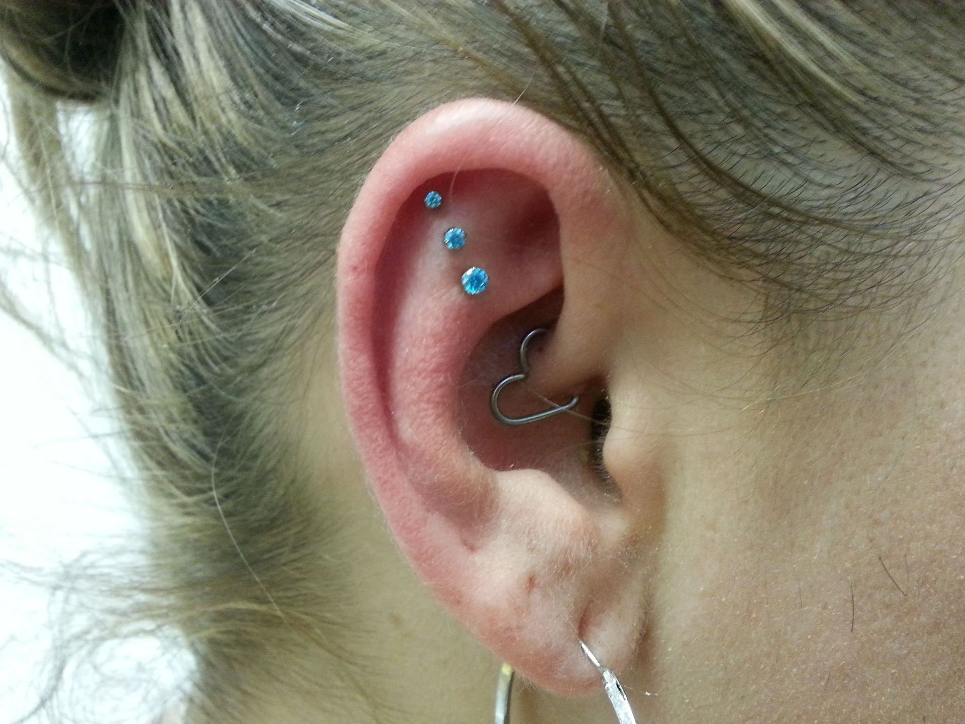 A close up of a woman 's ear with multiple piercings