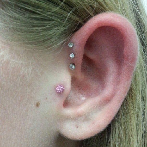 A close up of a woman 's ear with three piercings