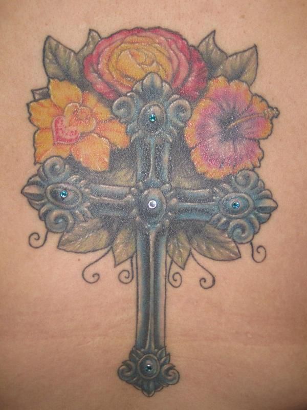 A tattoo of a cross with flowers on it