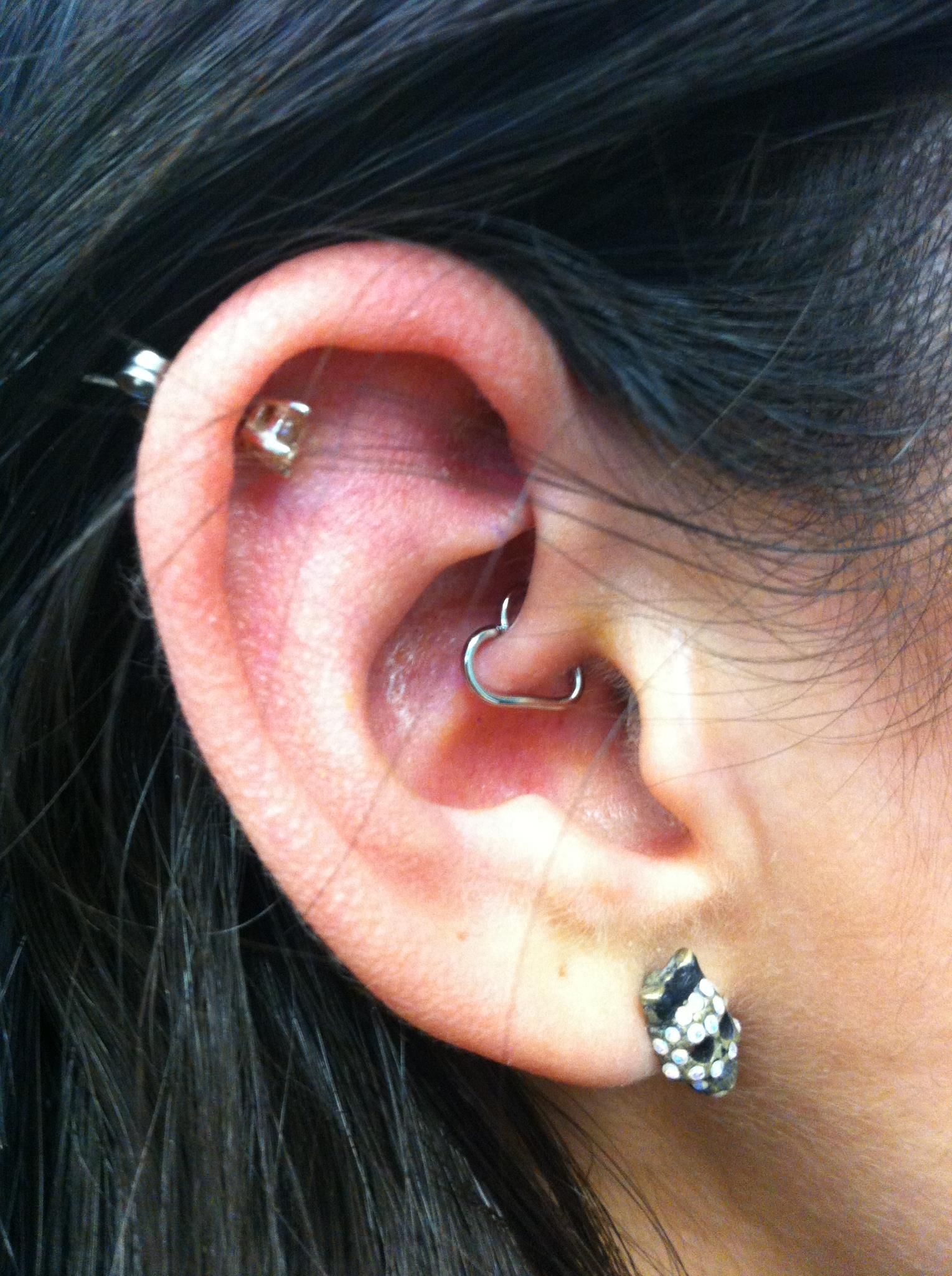 A close up of a woman 's ear with multiple piercings