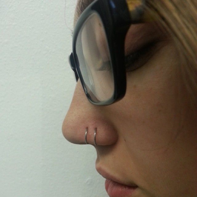 A close up of a woman wearing glasses and a nose ring