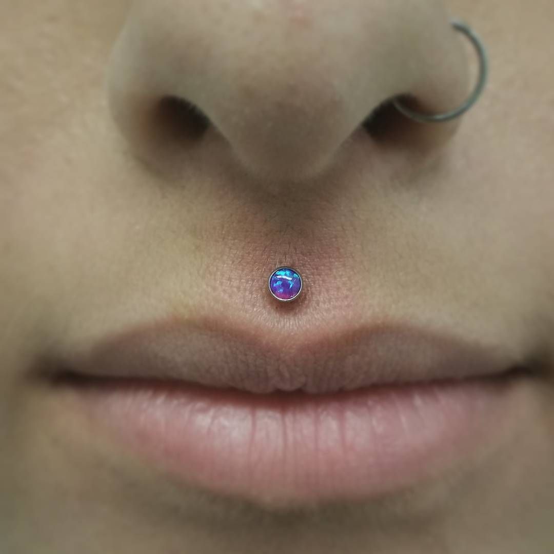 A close up of a woman 's face with a nose ring and a lip piercing.