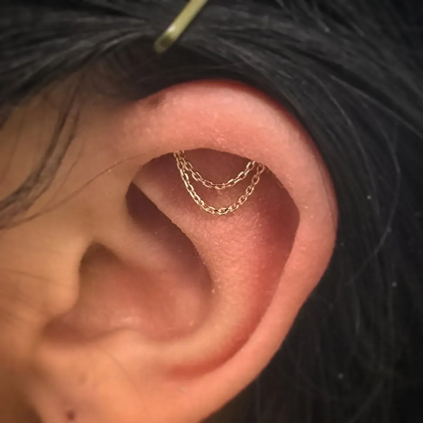 A close up of a woman 's ear with a chain in it