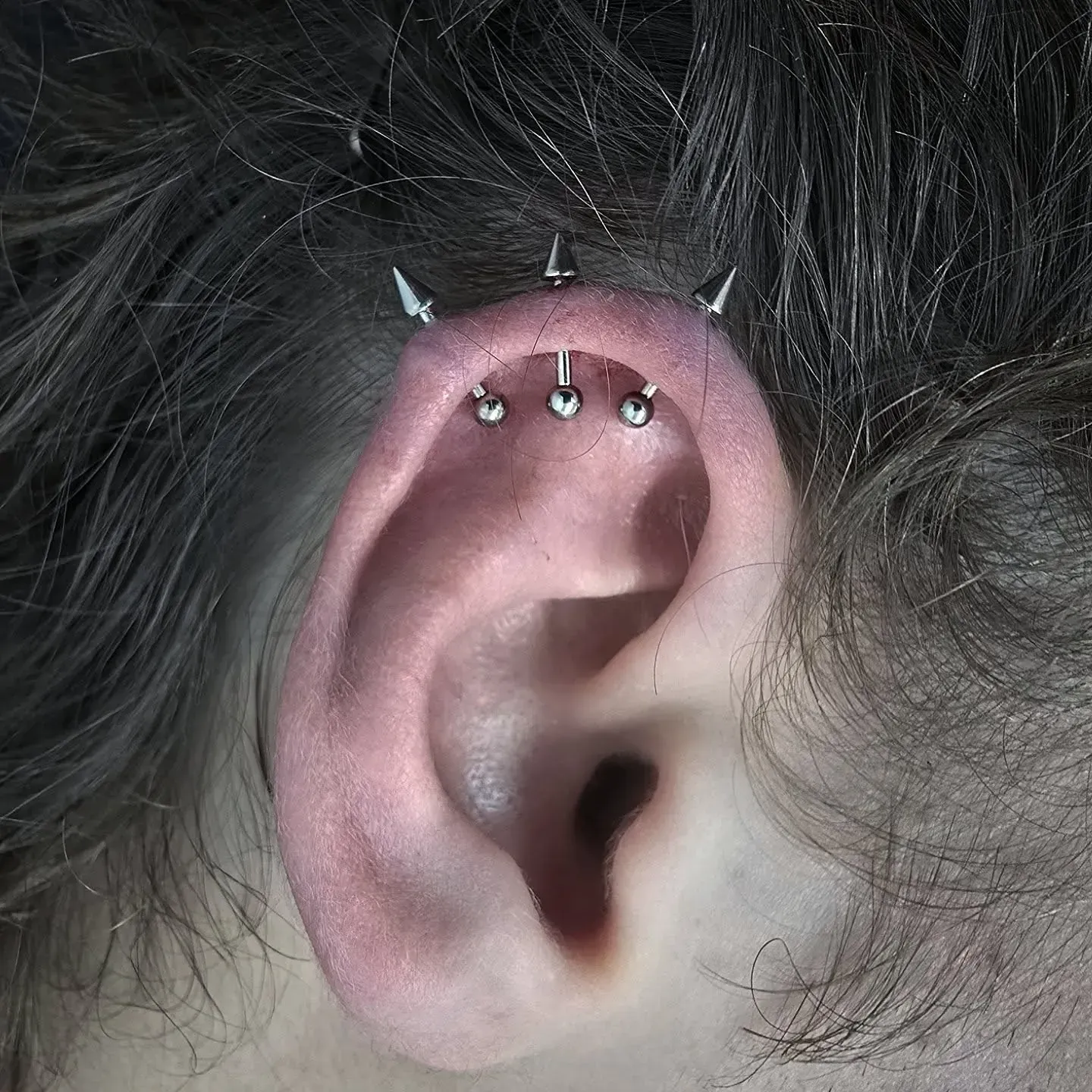 A close up of a person 's ear with piercings.
