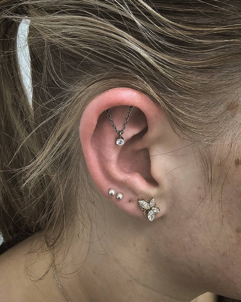 A close up of a woman 's ear with multiple piercings.