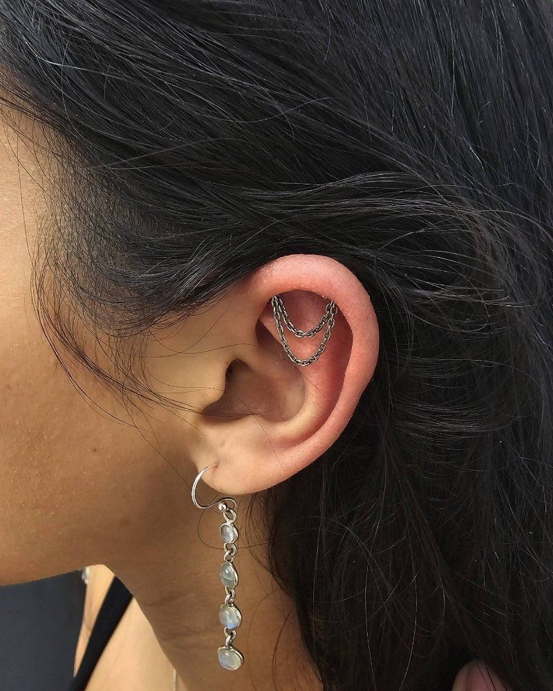 A close up of a woman 's ear with multiple piercings