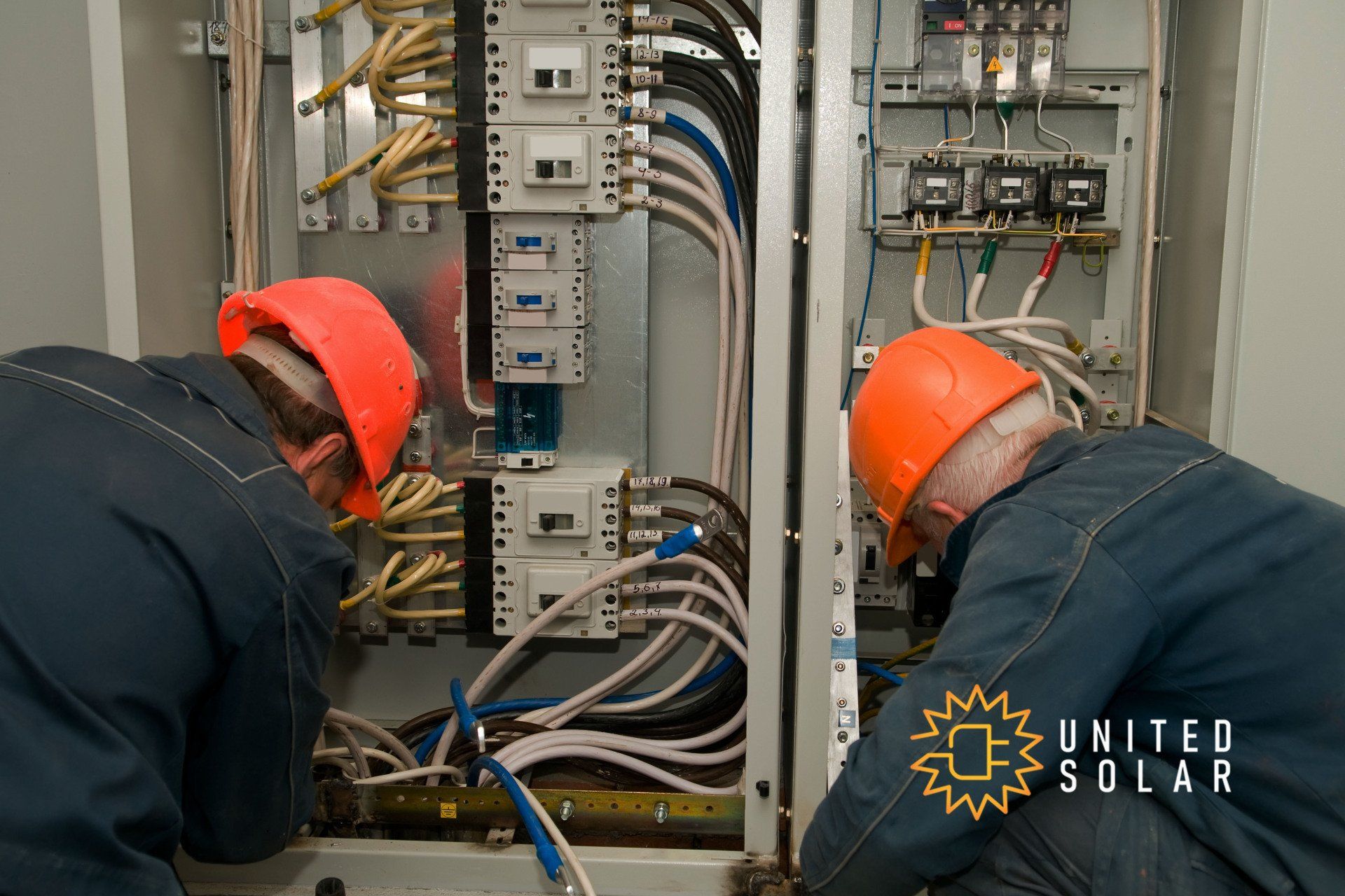 two electricians working on industrial panel