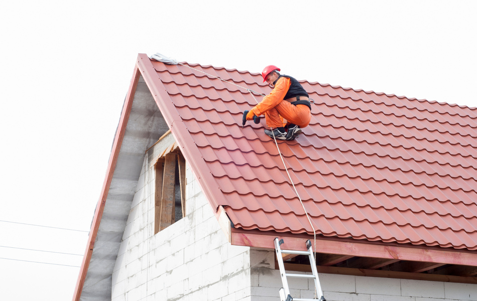 A man is sitting on a ladder on top of a roof.
