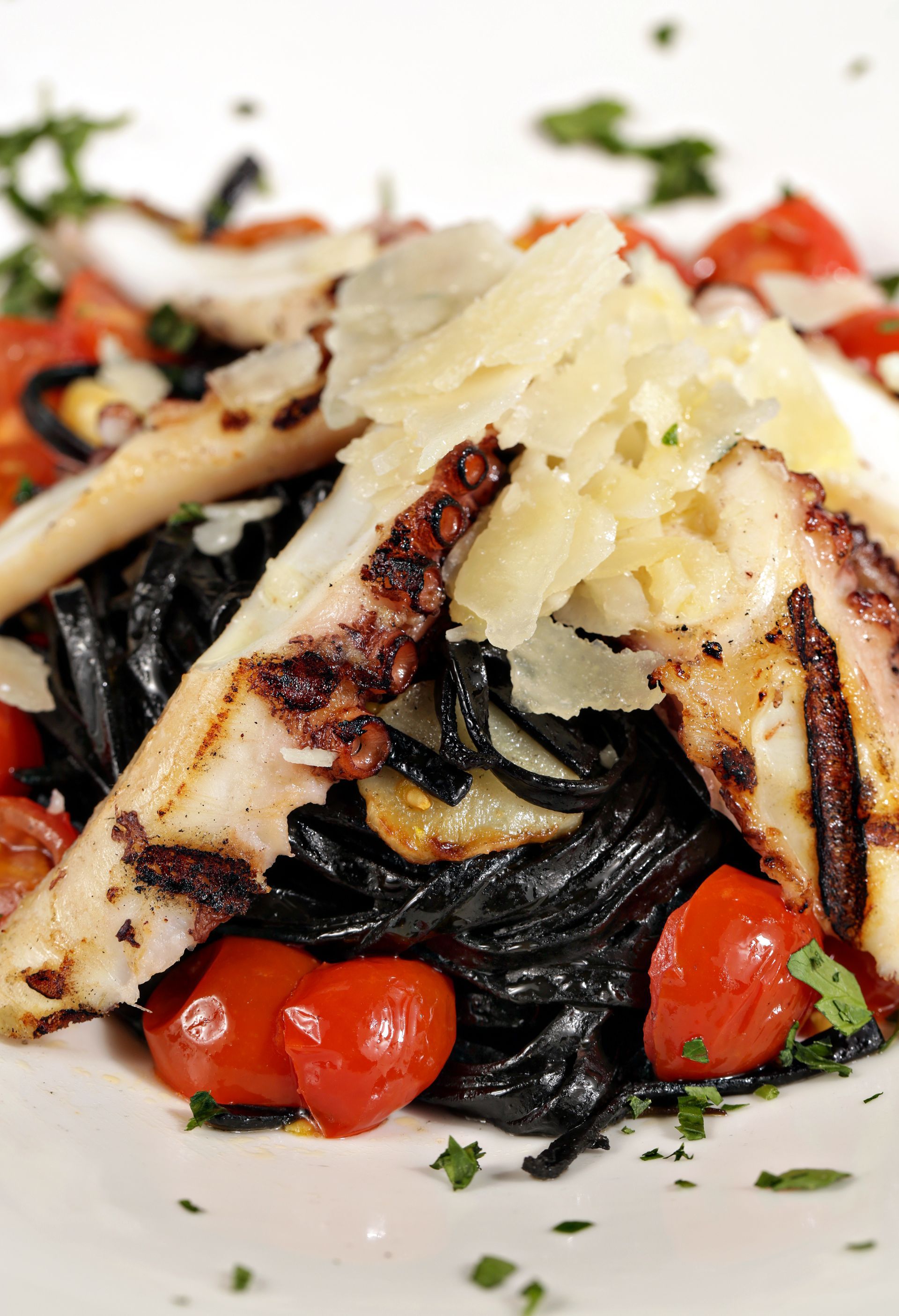 Squid ink pasta served with grilled octopus, cherry tomatoes, and shaved parmesan cheese.