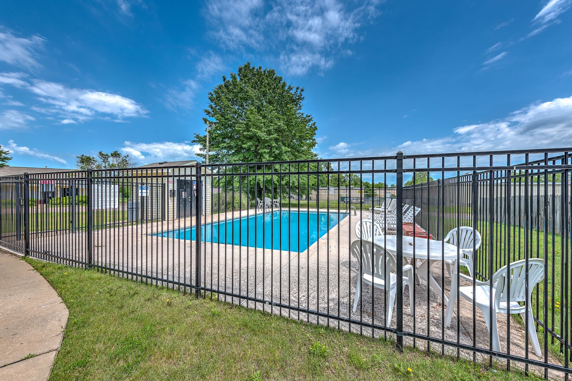 There is a swimming pool behind a metal fence.