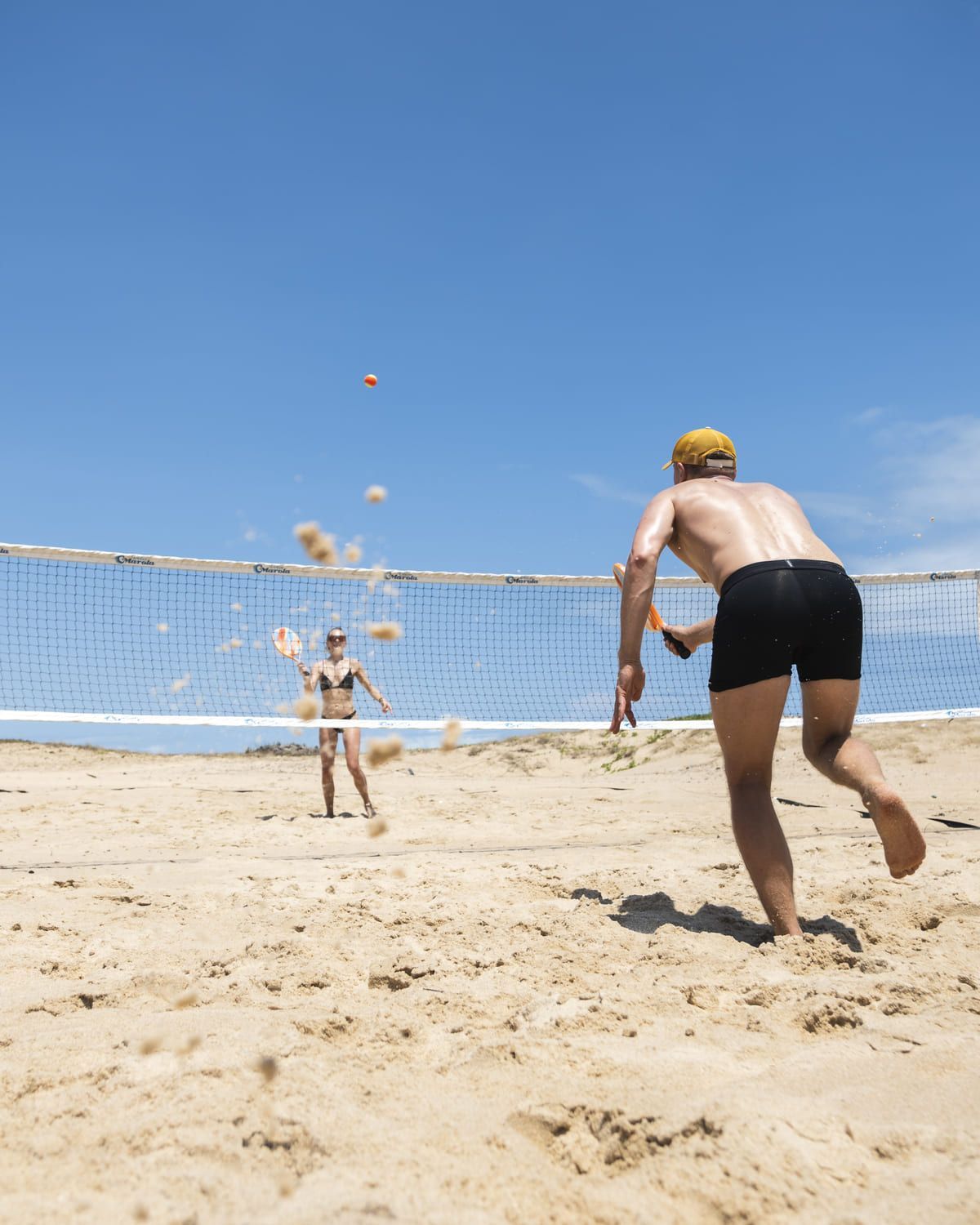 Um homem e uma mulher estão jogando vôlei na praia.
