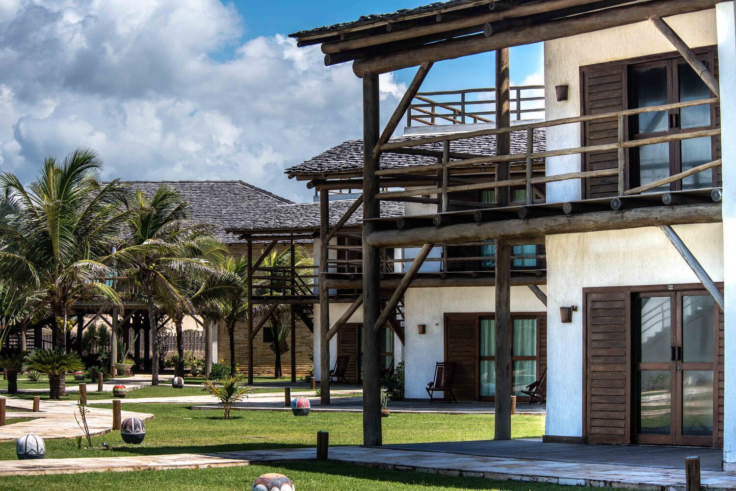 Uma casa branca com uma varanda de madeira é cercada por palmeiras