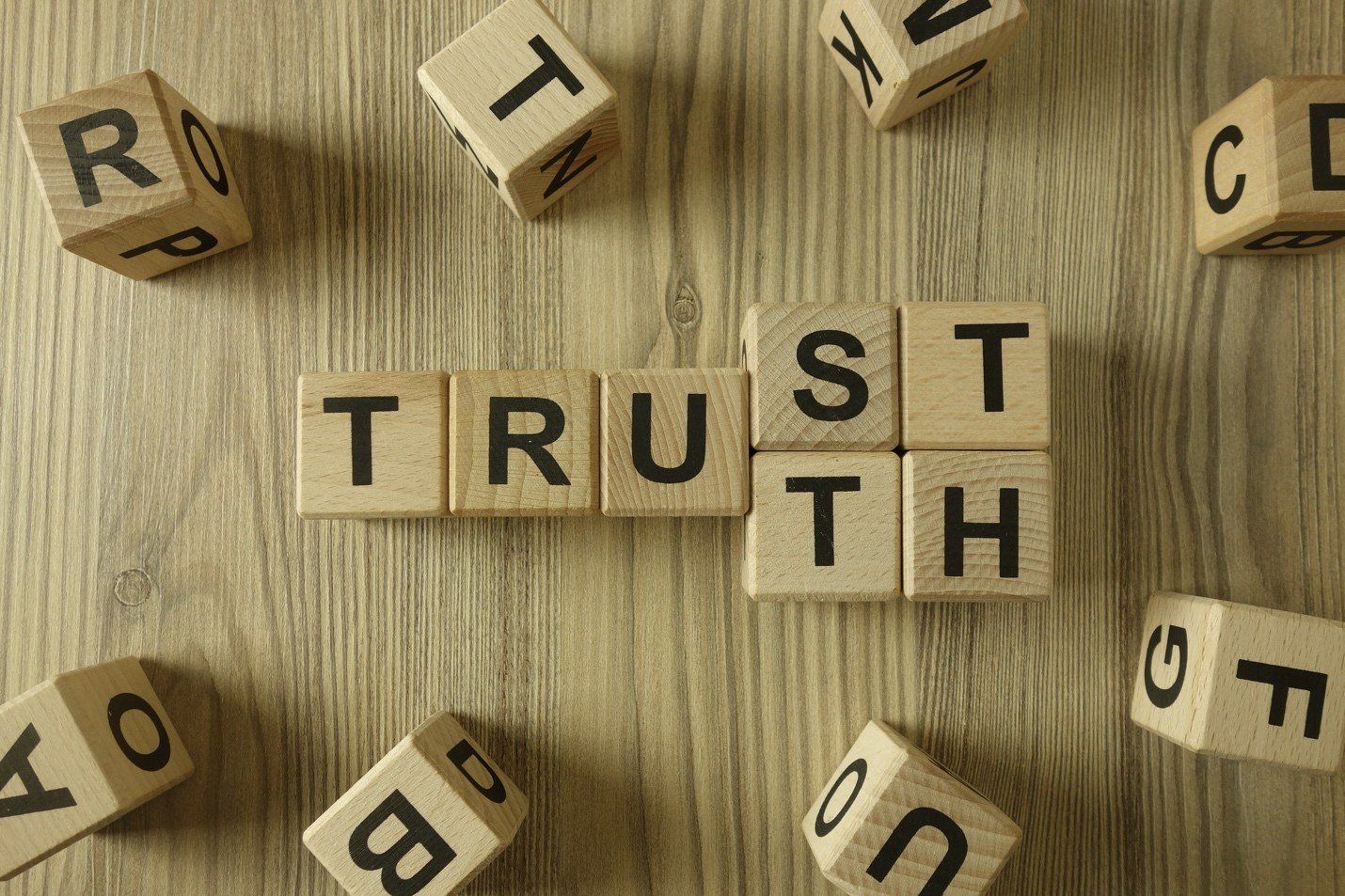 The word trust is written on wooden blocks on a wooden table.