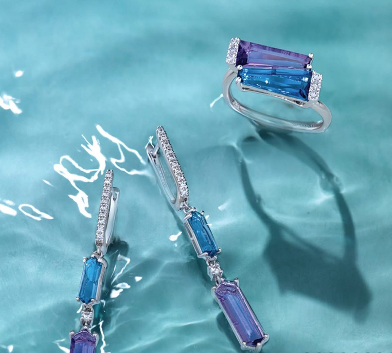 Jewelry set in water: ring and earrings with blue and purple gemstones.