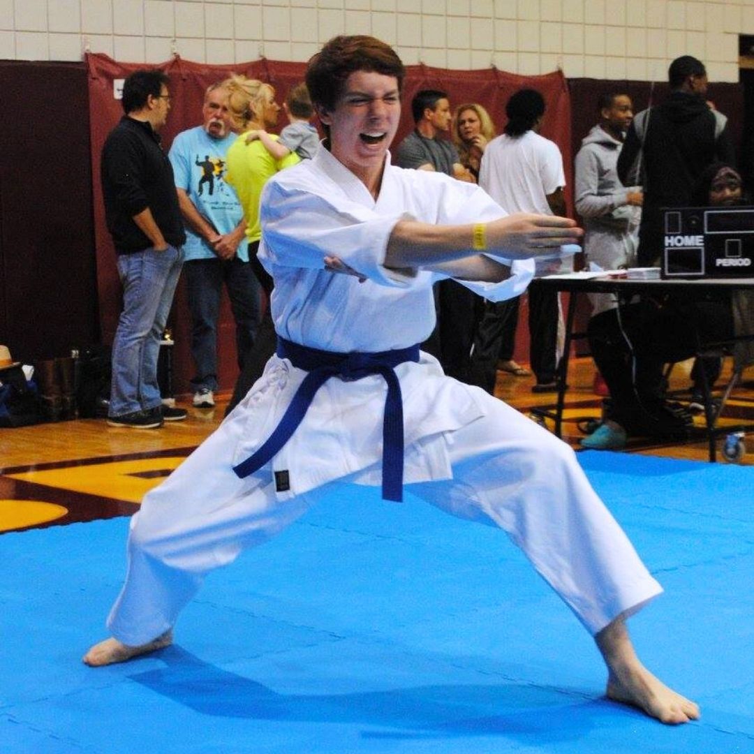 People practicing jiu-jitsu on mats, wearing gis in blue, black, and gray. Active grappling, gym setting.