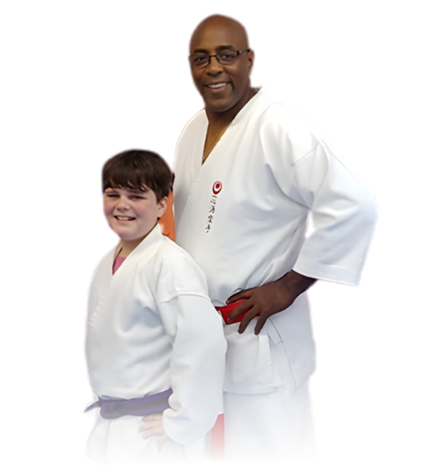 Man pointing, smiling, wearing black hoodie; arm tattoo visible.