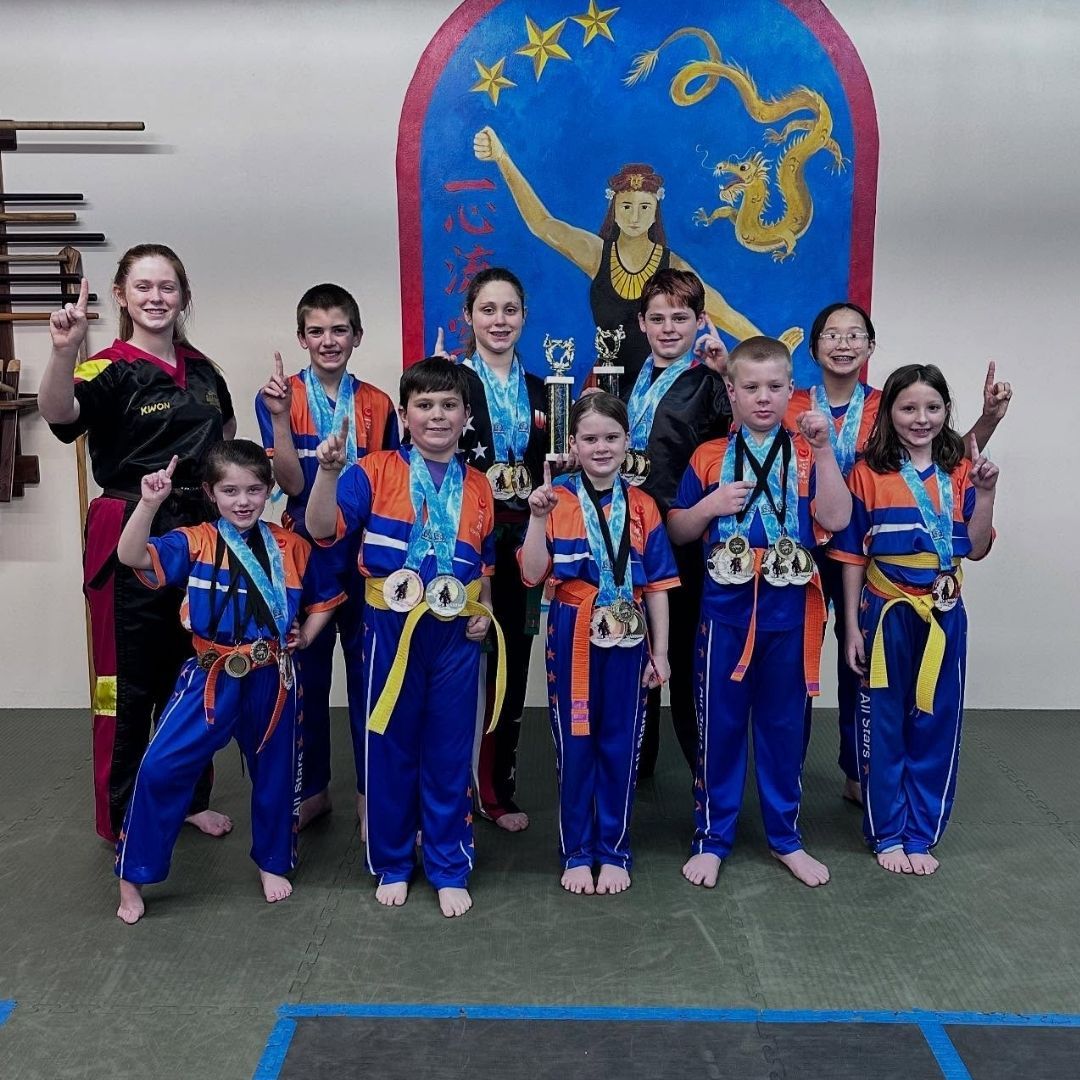 Two children grappling on a mat, one in a headlock.