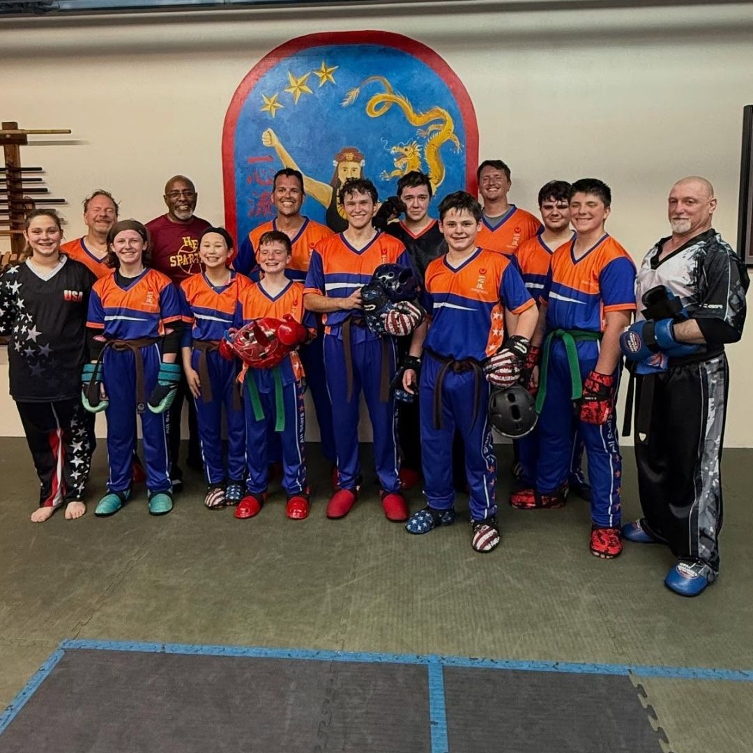 Four men in athletic gear, posing for a photo in a gym.