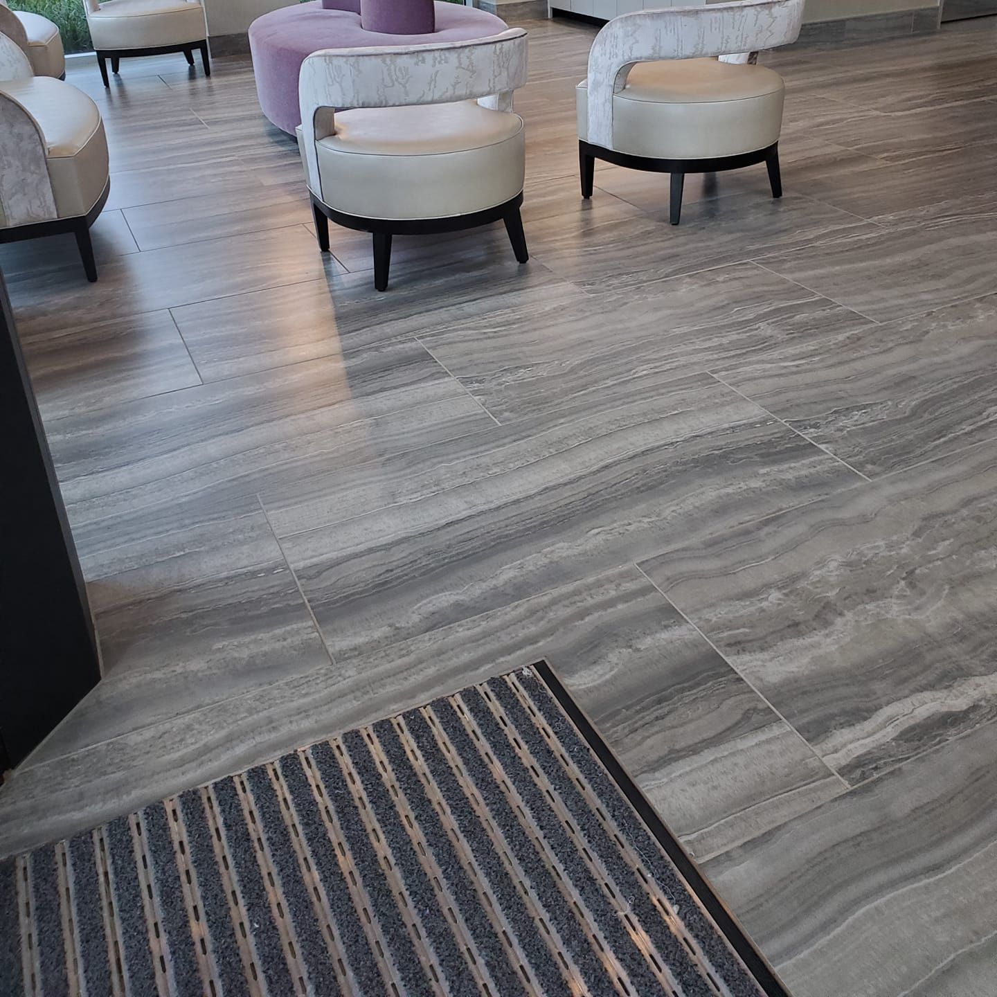 A room with chairs and a rug on the floor