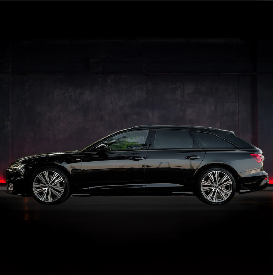 Audi A6 Avant nera parcheggiata, vista laterale, in un ambiente buio, che mette in risalto il design elegante dell'auto.