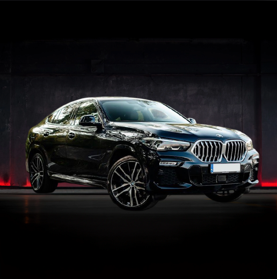 SUV BMW X6 nero parcheggiato davanti a uno sfondo scuro con illuminazione ambientale rossa.