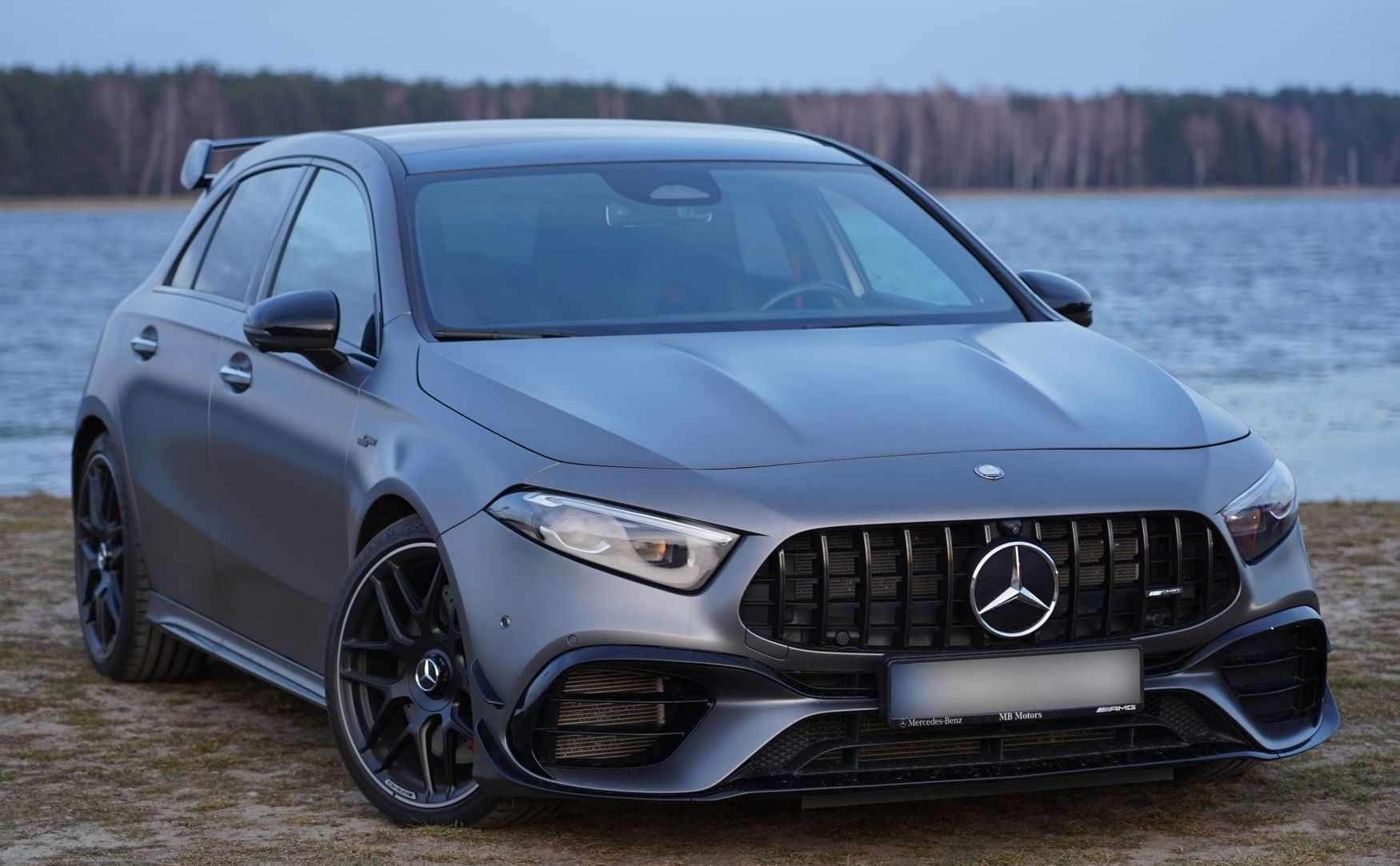 Una mercedes benz classe a è parcheggiata sulla spiaggia, vicino a uno specchio d'acqua.