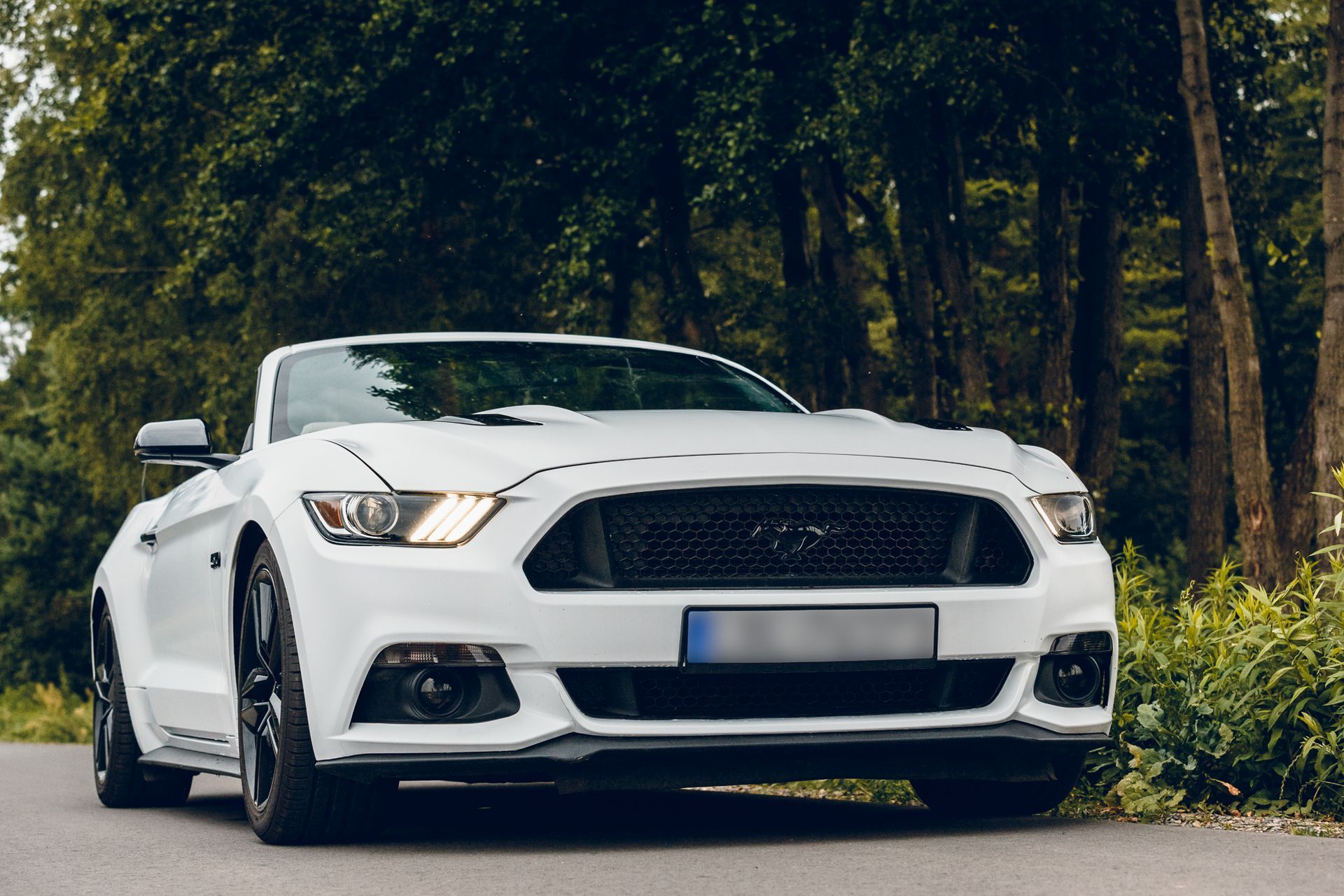 Una Ford Mustang decappottabile bianca è parcheggiata sul ciglio della strada.