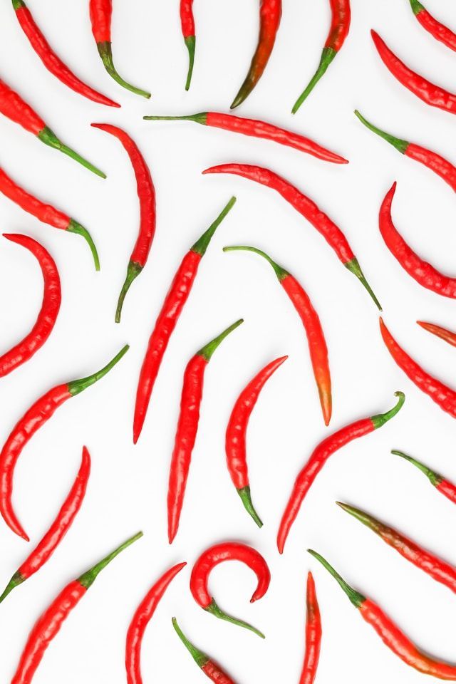 Red chili peppers scattered on a white background.