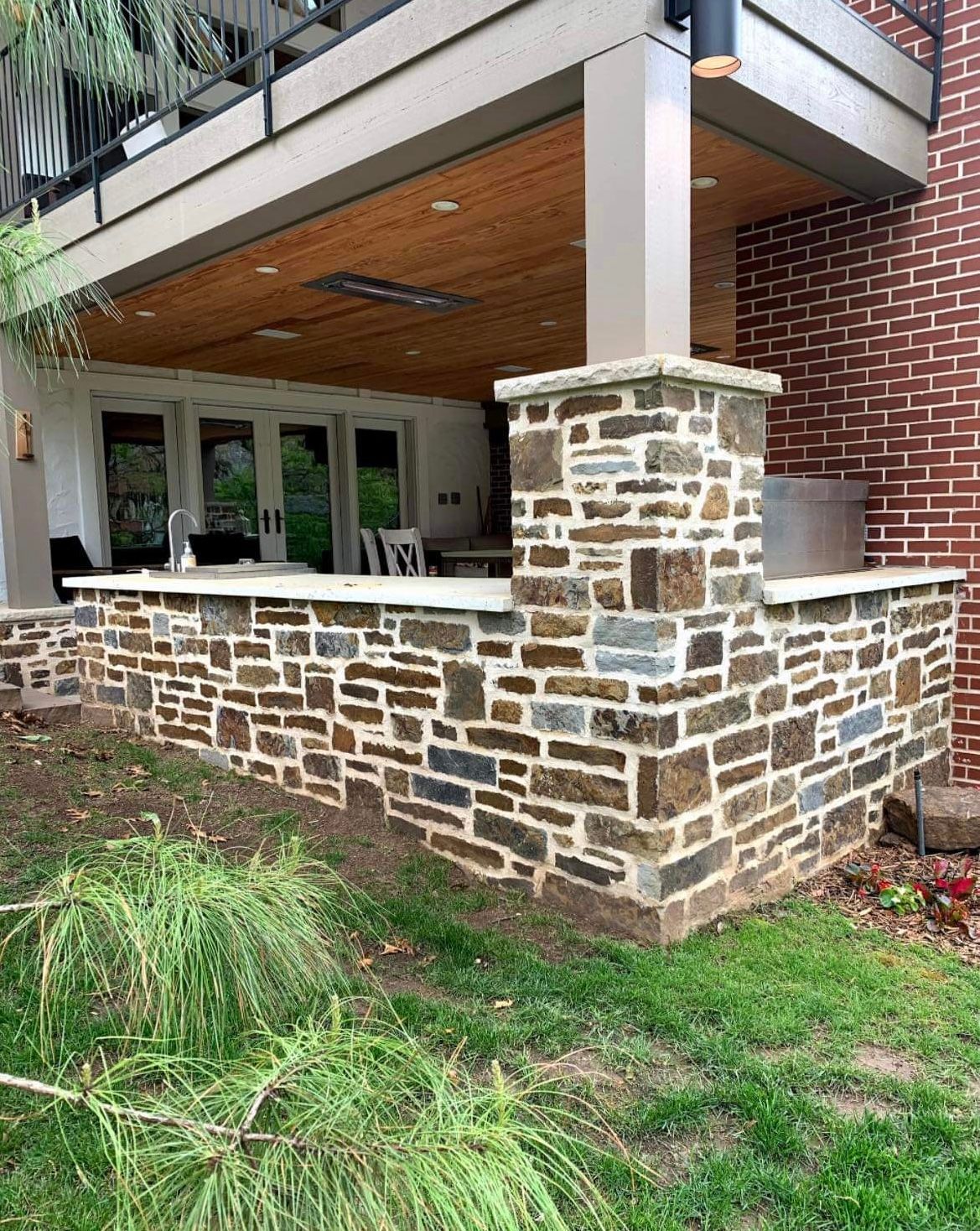 A stone wall surrounding a porch with a brick building in the background.