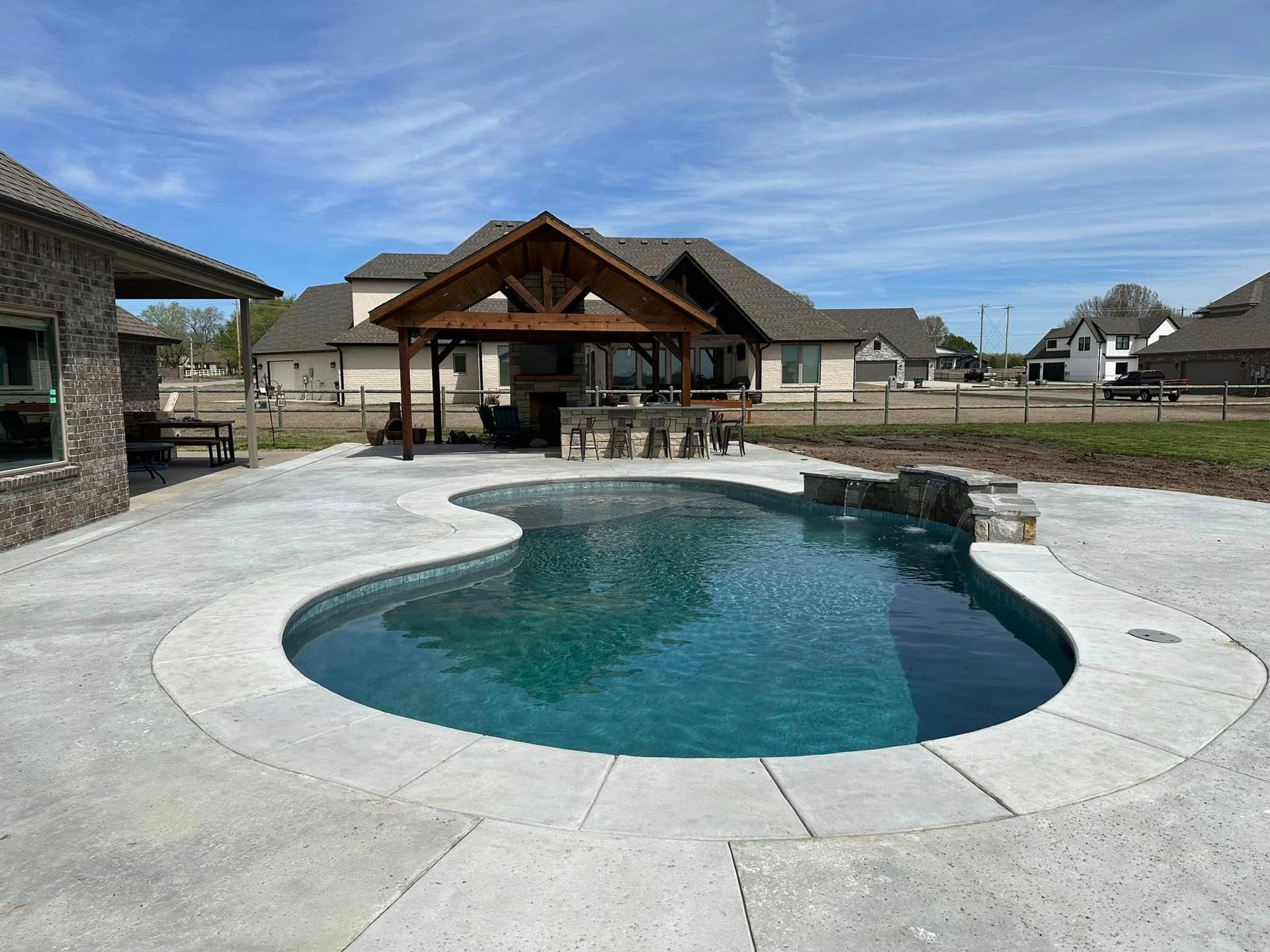 A large swimming pool is in the backyard of a house.