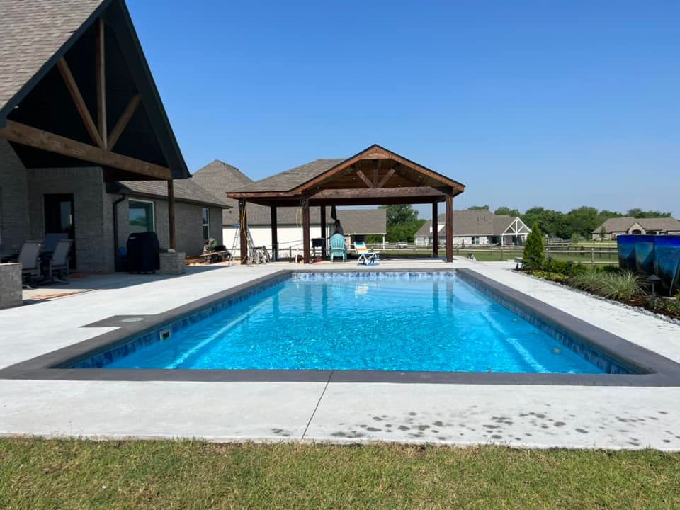 A large swimming pool is in the backyard of a house.