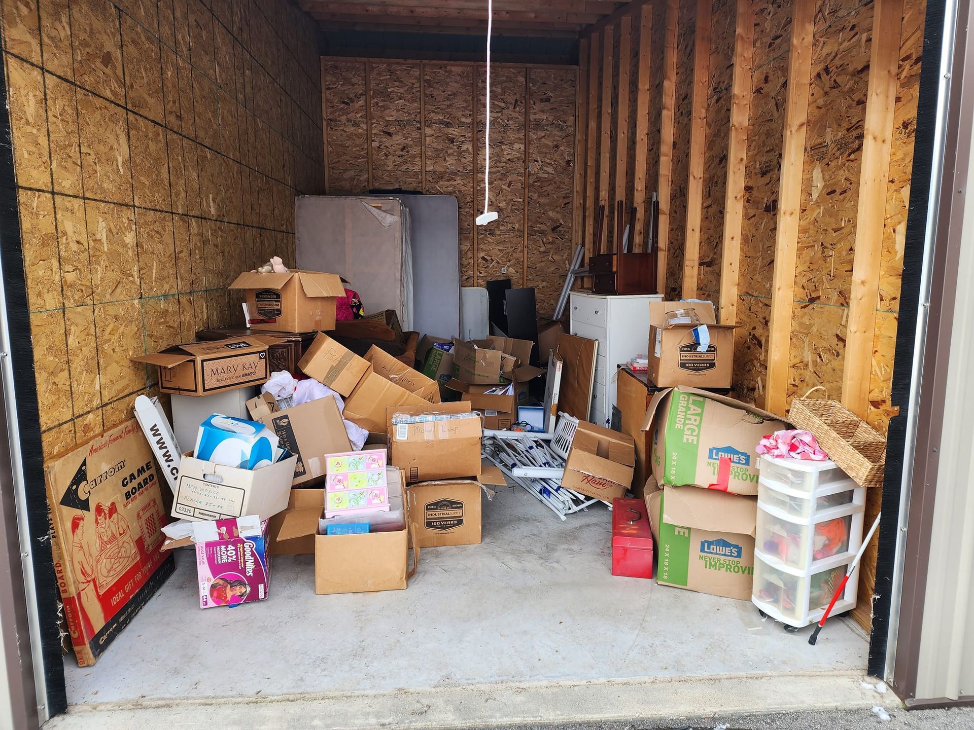 Storage unit filled with boxes, a mattress, and miscellaneous items.