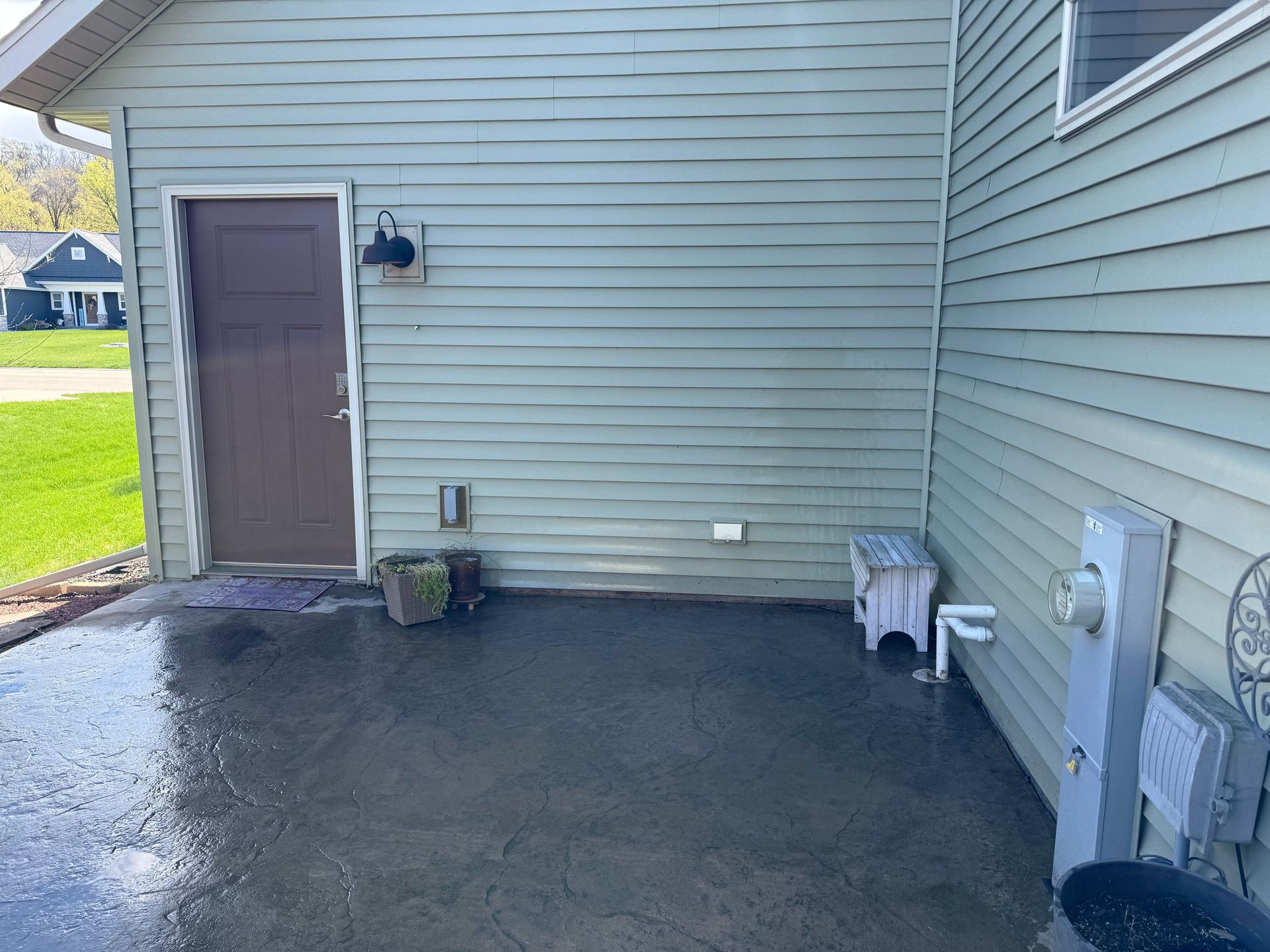 A house with a brown door and a concrete patio in front of it.