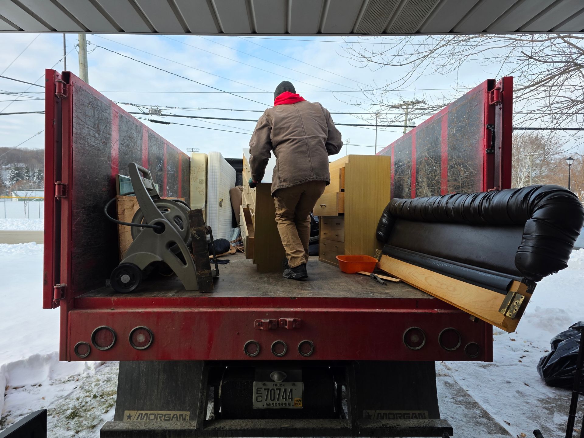 Two men loading furniture into a truck. One wears a red shirt with 