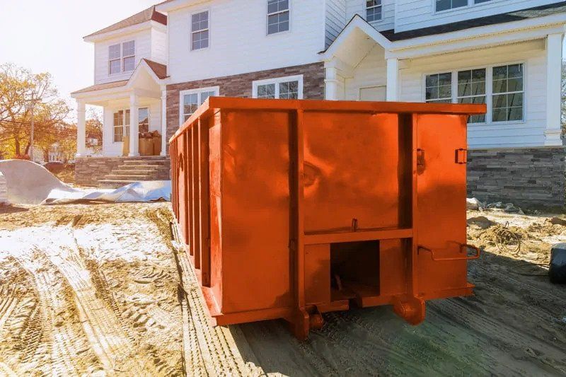 Orange dumpster in front of a house, possibly for construction or renovation debris.