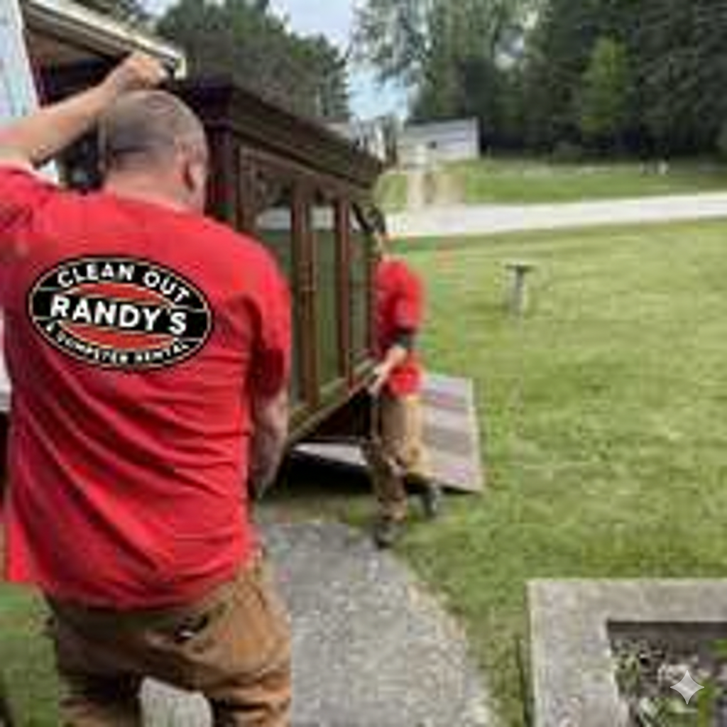 Two men moving furniture. One in red shirt with business logo, other in red. Outdoor setting.