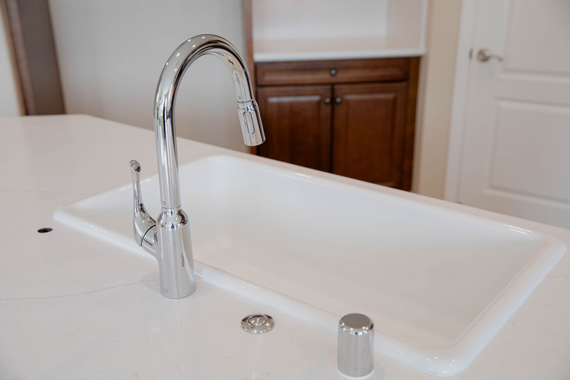 A kitchen sink with a chrome faucet on a white counter top in North County San Diego.