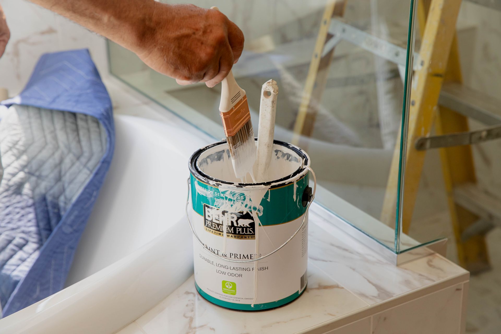 A person is holding a brush in a can of paint in San Marcos, California.