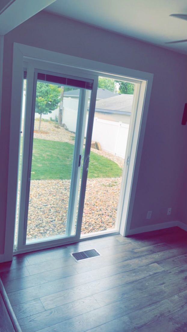 An empty room with a sliding glass door leading to a backyard.
