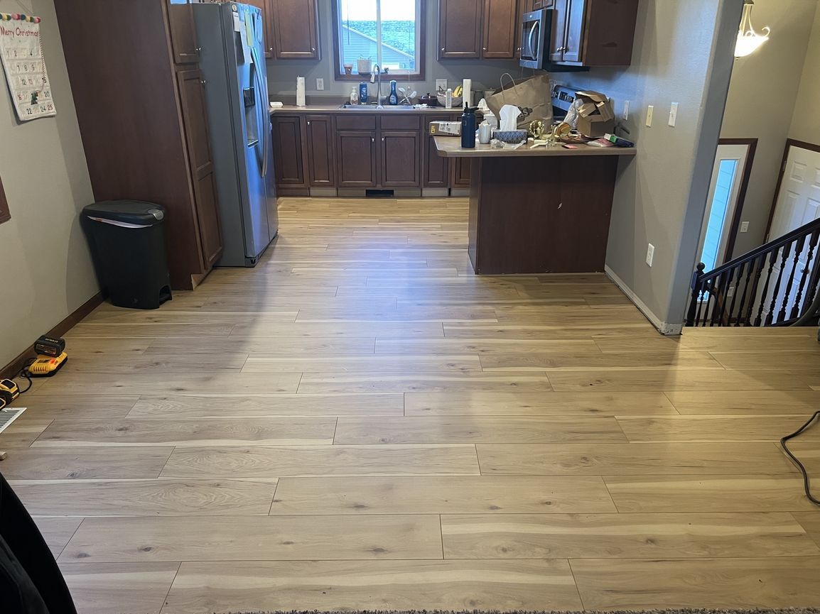 A kitchen with a wooden floor and a refrigerator.