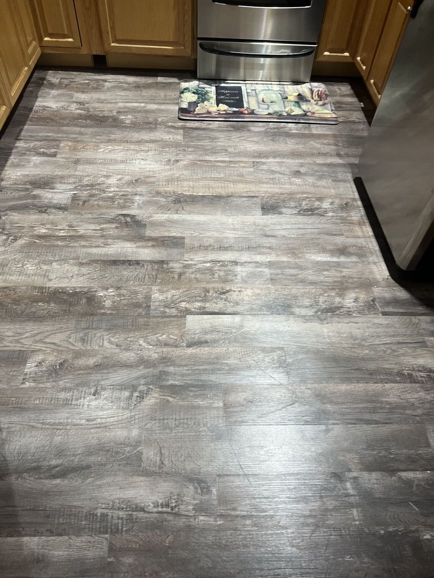 A kitchen with a wooden floor and stainless steel appliances.