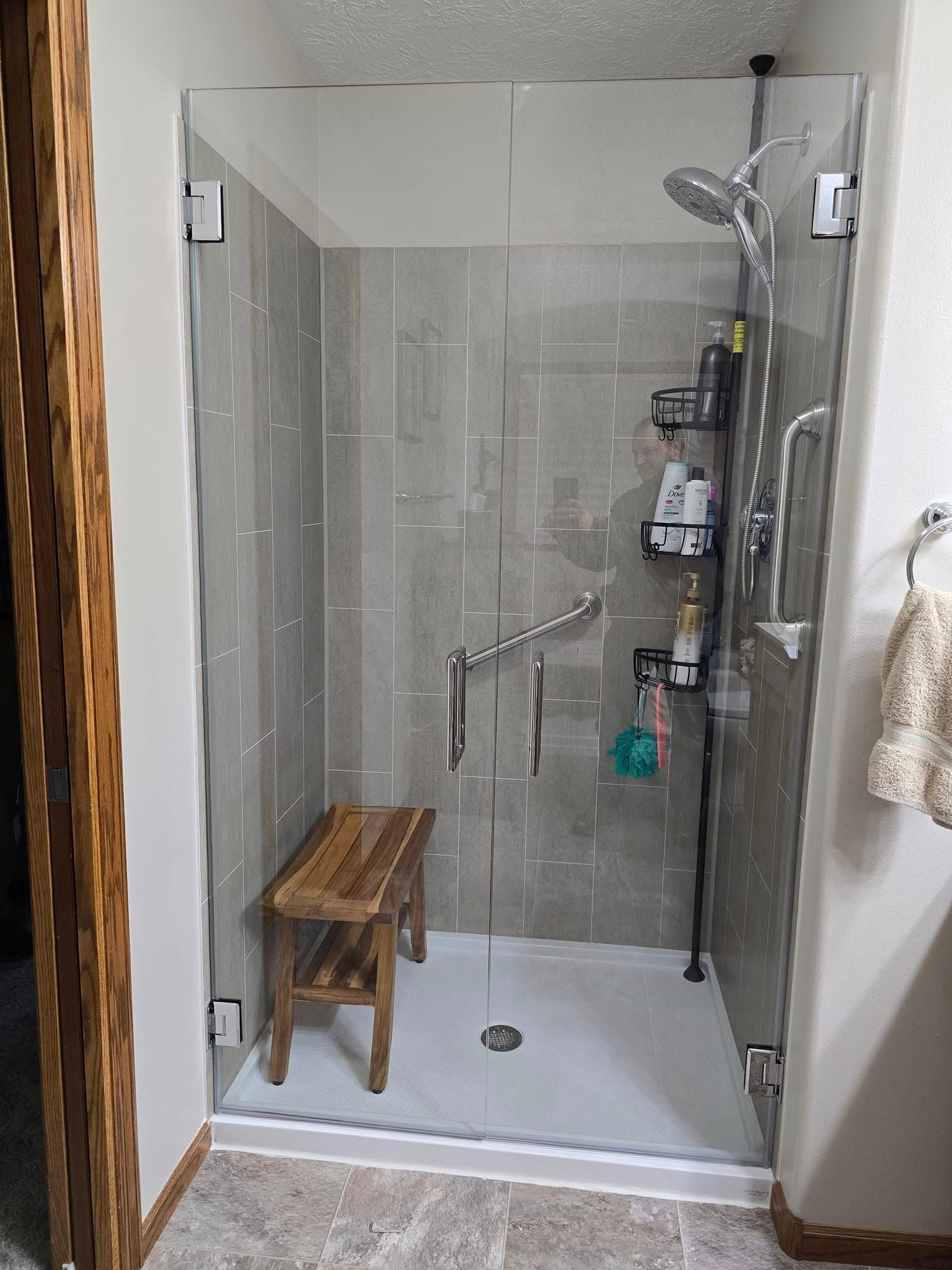 A bathroom with a walk in shower and a wooden bench.